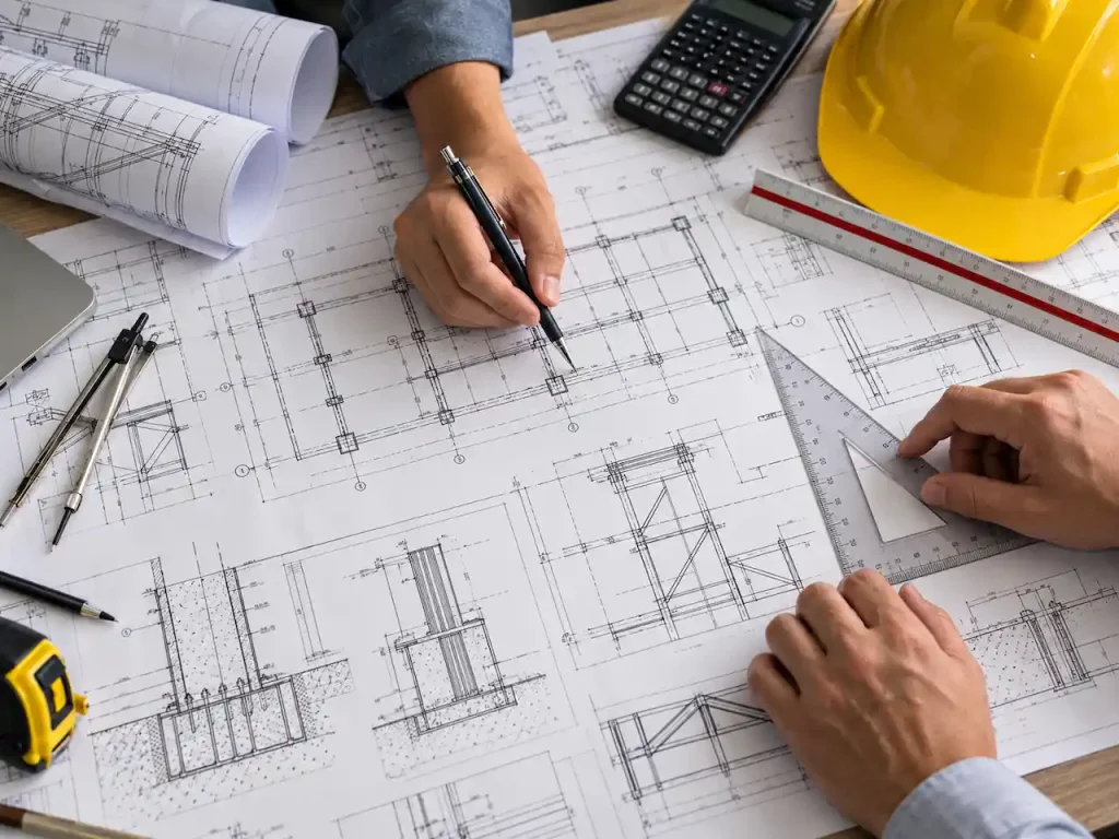 Structural engineers reviewing foundation and framing drawings with drafting tools, construction blueprints, and engineering details.